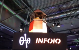 Ein Leuchtturm aus Holz vor einem OIO-Schild in der Kongresshalle.