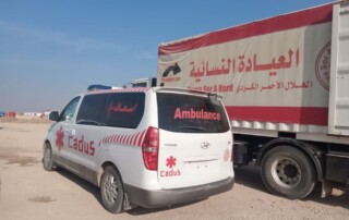 Ein Rettungswagen von CADUS steht vor einem LKW von Heyva Sor in Tal Tamr.